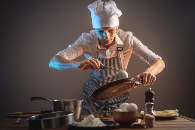 Um cozinheiro está derramando massa em uma frigideira quente e assando panquecas caseiras