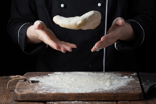 Um cozinheiro feminino joga uma massa de fermento nas mãos dela.