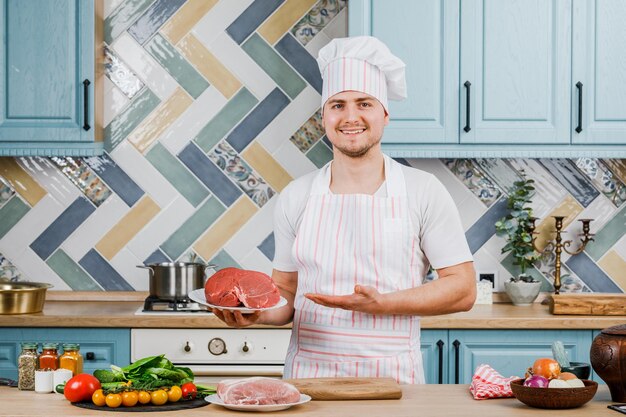 Um cozinheiro mantém a carne na cozinha. Conceito De Cozinha