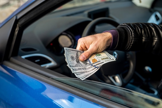 Um criminoso mau forte conta uma grande quantidade de notas de dólar dentro de um carro