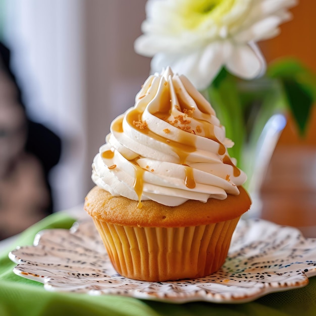 Um cupcake com cobertura de baunilha e caramelo salpicado por cima.