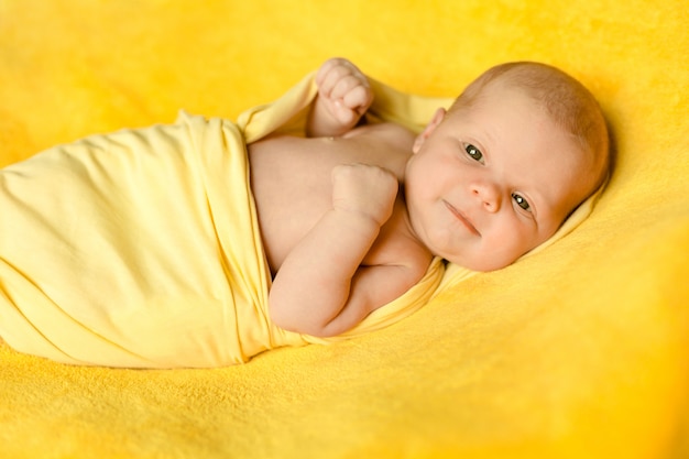 Foto um, cute, bebê recém-nascido, mentiras, ligado, um, cobertor amarelo, embrulhado, em, um, amarela, xadrez, e, sorrindo