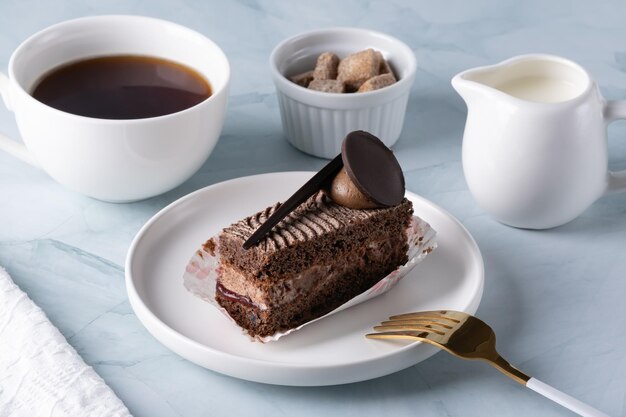 Um delicioso bolo de chocolate no prato e café na mesa de luz.