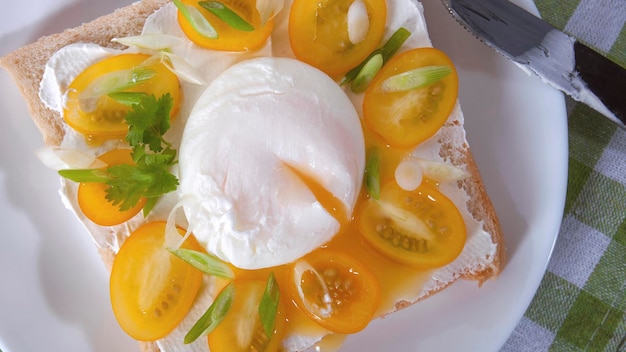 Um delicioso café da manhã com pão de ovo escalfado tomate cereja amarelo queijo e ervas Ovo escalfado no café da manhã Sanduíche com queijo tomate cereja amarelo ervas e ovo escalfado