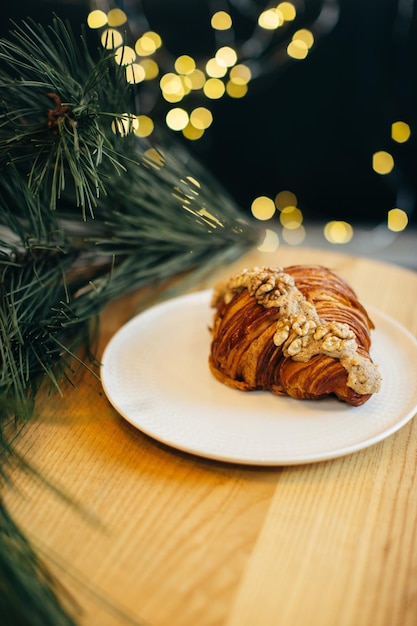 Um delicioso croissant em uma mesa em uma cafeteria decorada com luzes festivas de Natal