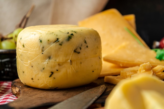 Um delicioso pedaço de queijo com especiarias e provolone sobre uma tábua de cortar sobre uma mesa rústica. Conceito de alimentação natural, orgânica e saudável.