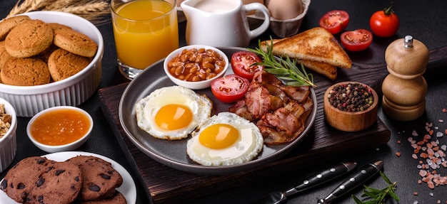 Um delicioso pequeno-almoço saudável nutritivo com ovos fritos bacon feijão um copo de suco biscoitos de aveia leite e geleia