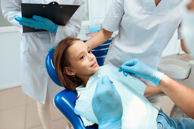 Um dentista está se preparando para tratar os dentes de uma menina.