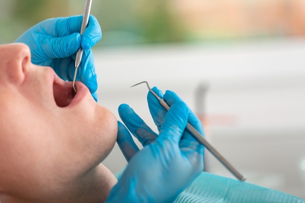 Um dentista feminino examina a cavidade oral do paciente com uma ferramenta com um espelho closeup retrato de um paciente com a boca aberta um médico em luvas segura um espelho dental