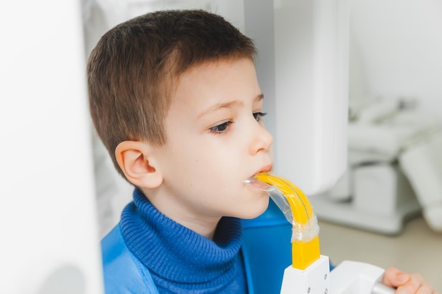 Um dentista masculino faz um raio-x panorâmico dos dentes de um menino usando uma máquina moderna de raio-x