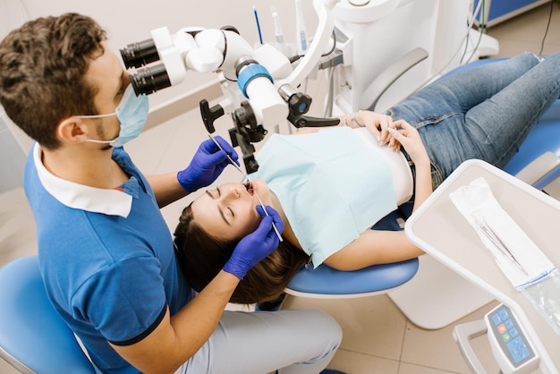 Um dentista olhando para o microscópio nos dentes do paciente