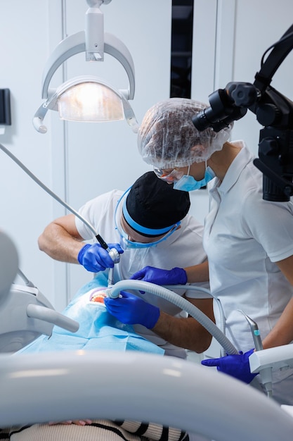 Um dentista profissional examina os dentes de um paciente com equipamento odontológico e segura instrumentos dentários perto de sua boca Cabine dental do dentista