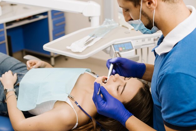 Um dentista trabalhando com paciente com broca odontológica