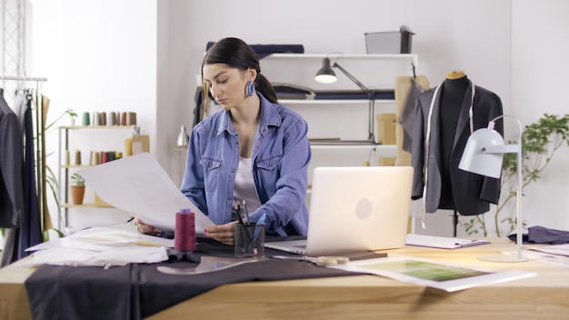 Um designer de moda profissional cria uma nova coleção trabalha em um laptop