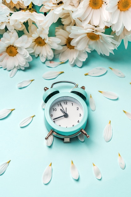 Um despertador azul suave em um buquê de margaridas. Conceito floral para férias