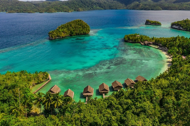 É um destino de férias imperdível Foto de alto ângulo dos bangalôs sobre a água ao longo da costa das Ilhas Raja Ampat na Indonésia