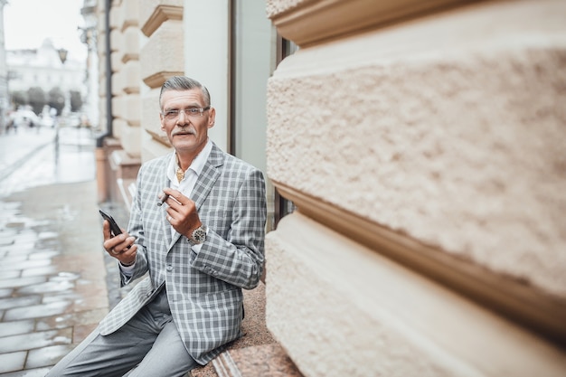 Um dia de verão, um velho bem sucedido com um cigarro cubano olhando para a câmera