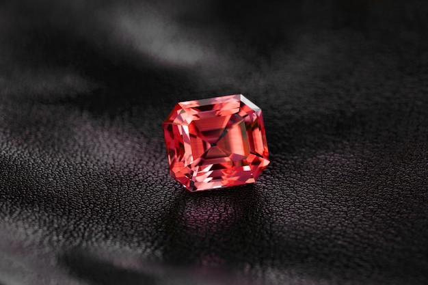 Um diamante vermelho fica em uma superfície de couro preto.