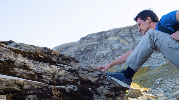 Um die Berge zu erobern, reist ein junger Mann in die Berge und klettert auf einen Felsen