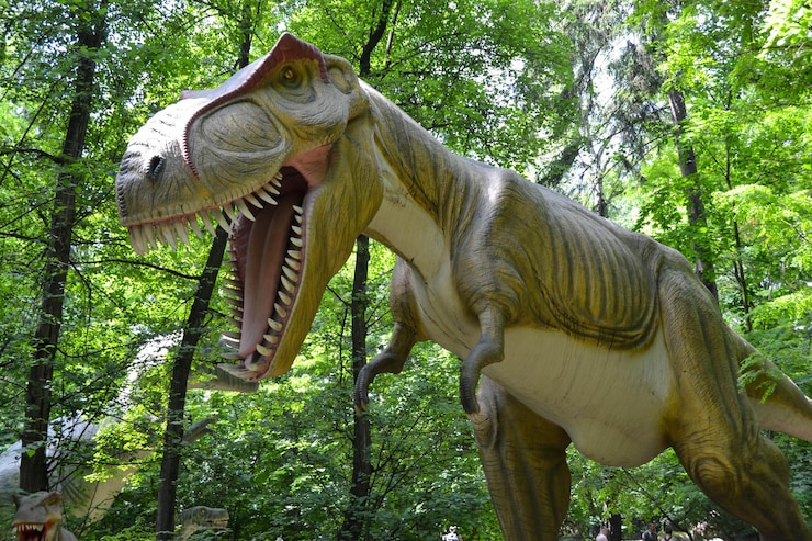 Foto um dinossauro com a boca aberta se posiciona contra o pano de fundo de uma densa floresta verde lagartos extintos