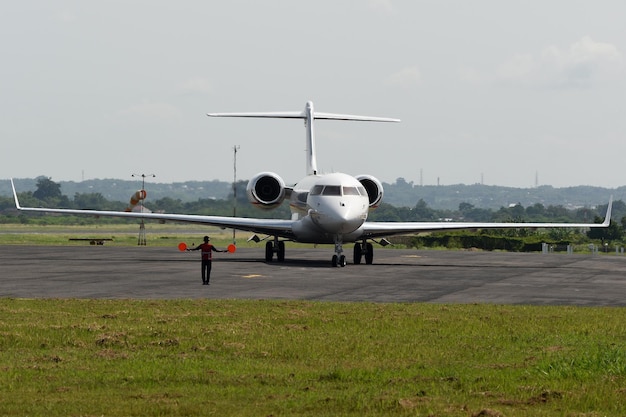 Foto um dirigente de aeronave guiando um jato privado para o espaço de estacionamento