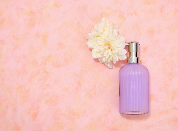 Um dispensador com sabonete líquido roxo e flores Espaço de cópia plana para texto Acessórios para spa e banho