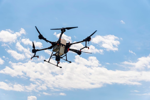 Um drone pulverizador sobrevoa um campo de trigo no céu azul com nuvens Agricultura inteligente e agricultura de precisão Um drone industrial no céu
