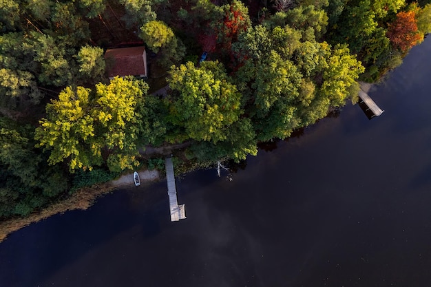 Foto um drone voa sobre um enorme lago azul com um píer de madeira entre as florestas em um dia sem nuvens de outono a