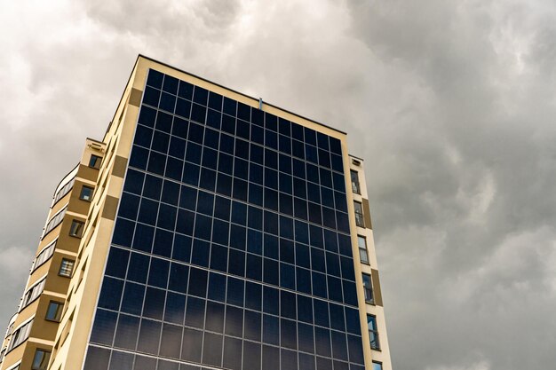 Um edifício moderno energeticamente eficiente no contexto das nuvens Edifício residencial de vários andares com painéis solares na parede Fontes de energia renováveis na cidade