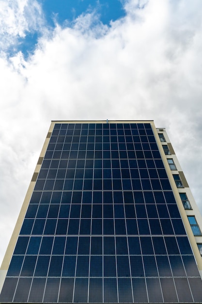 Um edifício moderno energeticamente eficiente no contexto das nuvens Edifício residencial de vários andares com painéis solares na parede Fontes de energia renováveis na cidade