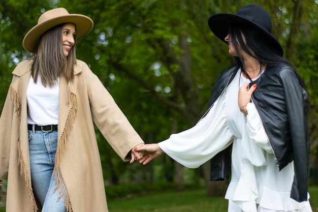 Um elegante casal de lésbicas de mãos dadas e andando no parque