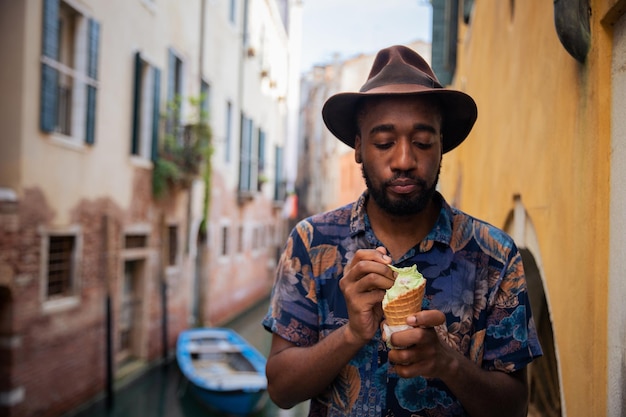 Um elegante garoto africano de férias em Veneza come um sorvete