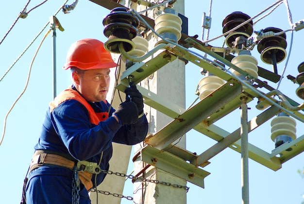 Um eletricista em um poste elétrico muda um isolador danificado