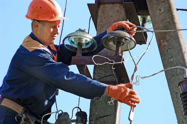 Um eletricista em um poste elétrico muda um isolador danificado