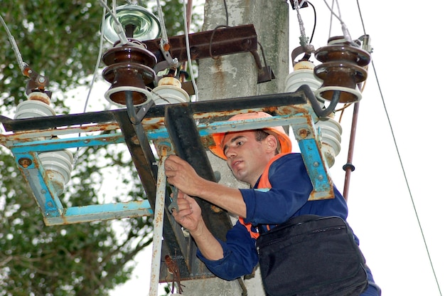 Um eletricista em um poste elétrico muda um isolador danificado