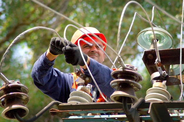 Um eletricista em um poste elétrico muda um isolador danificado