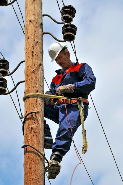 Um eletricista em um poste elétrico se prepara para substituir um isolador danificado.