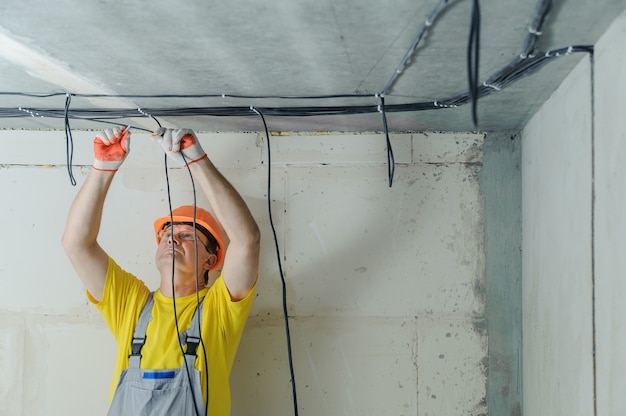 Um eletricista está fixando cabos elétricos no teto