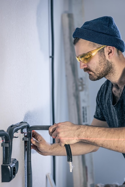 Um eletricista está montando tomadas elétricas na parede branca dentro de casa