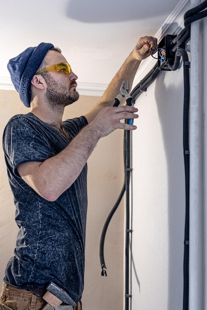 Foto um eletricista está montando tomadas elétricas na parede branca dentro de casa