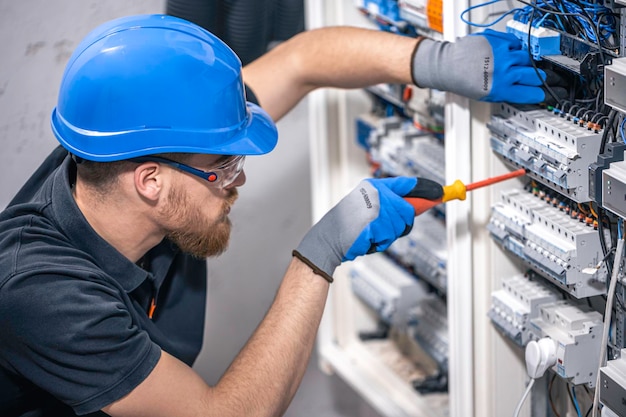 Um eletricista masculino trabalha em uma central elétrica com um cabo de conexão elétrica