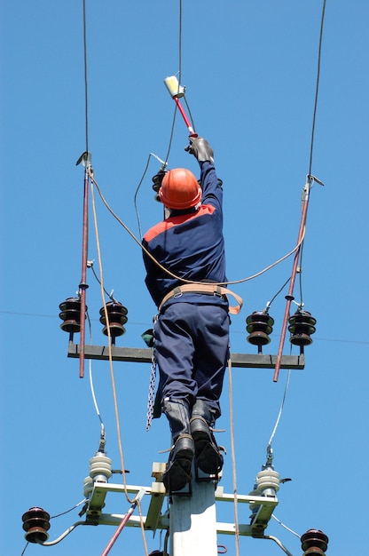 Um eletricista mede a tensão em uma linha de energia antes de instalar o aterramento.
