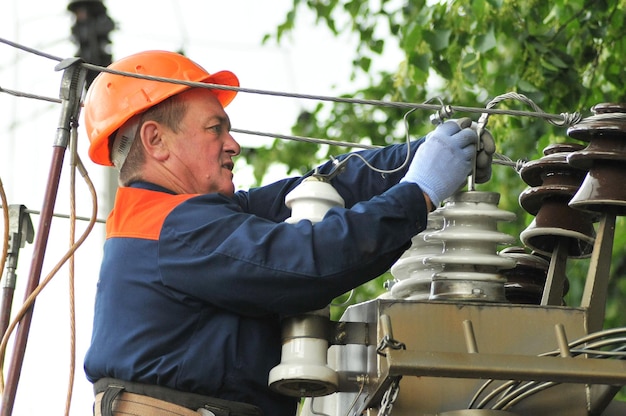 Um eletricista no gabinete de controle elétrico troca um isolador danificado.