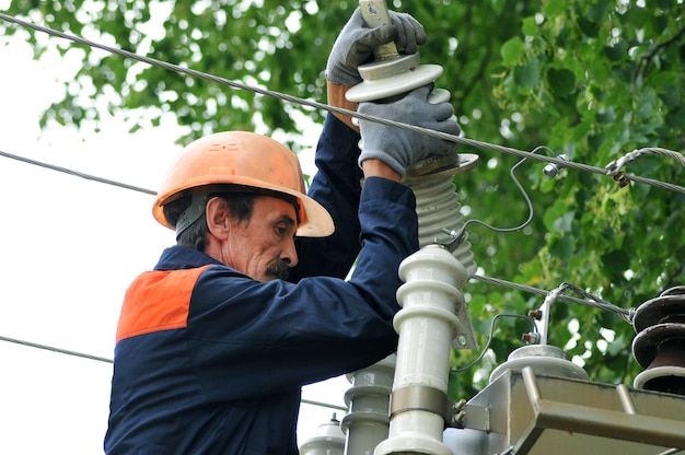 Um eletricista no gabinete de controle elétrico troca um isolador danificado.