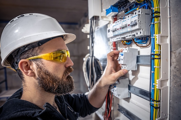 Um eletricista trabalha em uma mesa telefônica com um cabo elétrico de conexão.