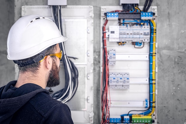 Um eletricista trabalha em uma mesa telefônica com um cabo elétrico de conexão