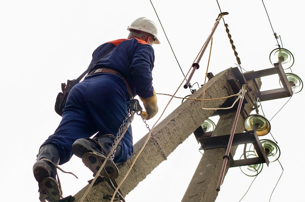 Um eletricista verifica a instalação do aterramento em uma linha de energia antes de repará-la.