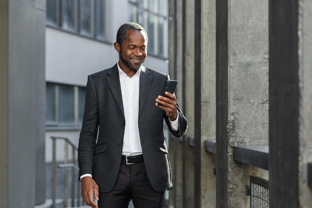 Um empresário afro-americano de sucesso em um terno de negócios está parado na rua perto de um