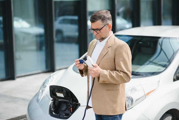 Um empresário carrega um carro elétrico