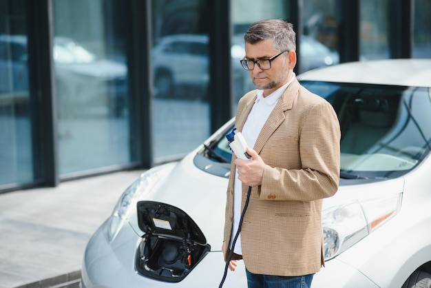 Um empresário carrega um carro elétrico